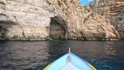 A boat approaches the Blue Grotto in Malta, surrounded by limestone cliffs and deep blue waters. A popular tourist destination known for its sea caves and crystal-clear reflections.