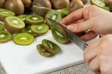 The process of cutting fresh ripe kiwi into slices with a knife.