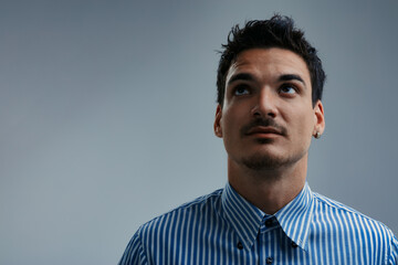 Pensive young adult businessman looking up with hope