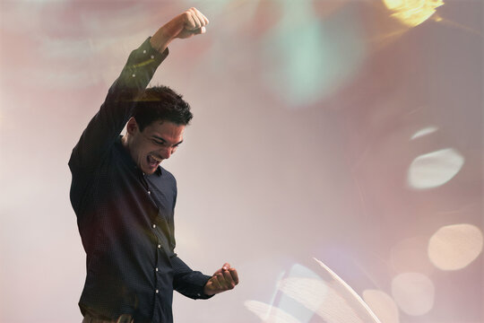 Young businessman celebrating success with raised arms and clenc