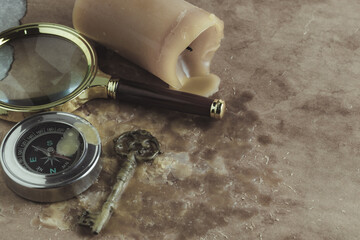 Vintage key, compass, magnifying glass and candle on background old paper.