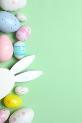 Happy Easter. Colorful eggs and Easter bunny ears on a pastel blue background, space for text or advertising