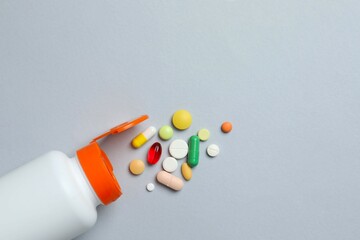 White bottle with pills on gray background, top view