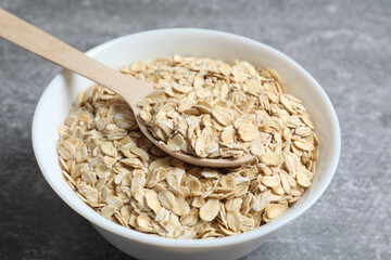 Composition with oatmeal flakes on gray background. Cooking breakfast