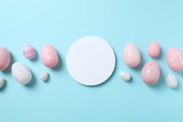 Happy Easter. Colorful eggs with white paper card on a pastel blue background, space for text or advertising