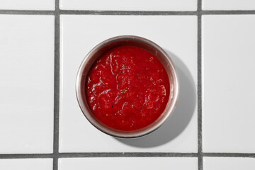 Red sauce on a background of white tiles close-up