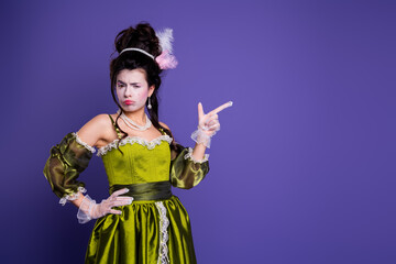 Elegant woman in a historic green costume on purple background portraying baroque era style