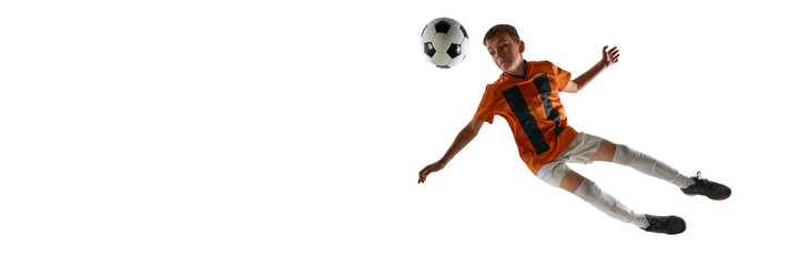 Dynamic image of teen boy, soccer player in orange jersey and white shorts, training, growing skills, in motion with ball against white studio background. Sport, education, competition, game concept © master1305