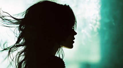 Naklejka premium Silhouette of woman's hair against a soft, diffused glow, exuding mystery and ethereal beauty through the interplay of light and shadow.