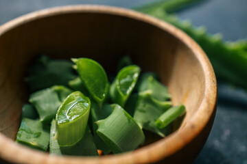 Freshly cut aloe vera pieces in a wooden bowl. The juicy green plant is known for its soothing gel...