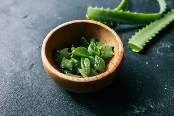 Freshly cut aloe vera pieces in a wooden bowl. The juicy green plant is known for its soothing gel...