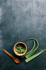 Freshly cut aloe vera leaves and pieces in a wooden bowl on a dark textured background. A natural ingredient for skincare, healing, and wellness. Herbal remedy for hydration and nourishment