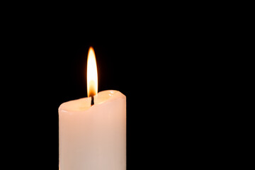 Burning candle with soft glowing flame in darkness for relaxation and meditation