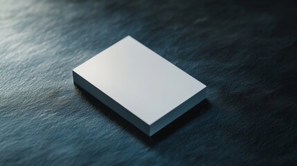 A compact, white rectangle lies on a dark surface, offering a contrast that suggests balance and minimalist design.