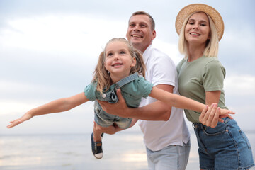 Happy family spending time together near sea on sunny summer day