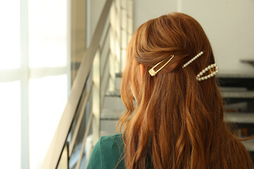 Teenage girl with stylish hair clips indoors, back view. Space for text