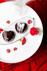 Chocolate cake with Belgian dark chocolate, raspberries, heart-shaped dessert in chocolate glaze, raspberry jam, creamy souffle, flatlay on a light background with red flowers, wedding cakes
