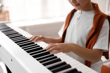 Fototapeta premium Boy playing synthesizer at home, closeup. Electronic musical instrument
