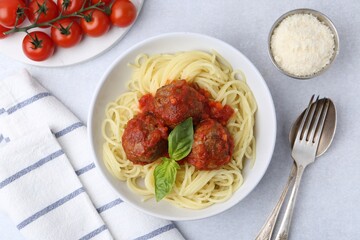 Delicious pasta with meatballs in bowl served on light table, flat lay