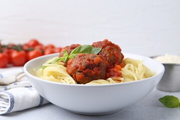 Delicious pasta with meatballs in bowl on light table, closeup