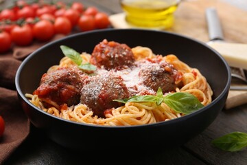 Delicious pasta with meatballs and cheese in bowl on wooden table, closeup