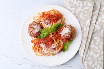 Delicious pasta with meatballs, basil and cheese on light textured table, top view