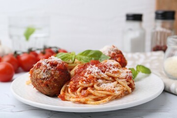 Delicious pasta with meatballs, basil and cheese on light textured table, closeup