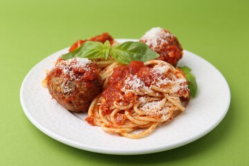 Delicious pasta with meatballs, cheese and basil on green table, closeup