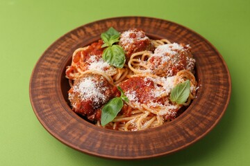 Delicious pasta with meatballs, cheese and basil on green table, closeup
