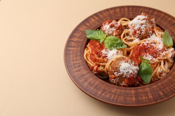 Delicious pasta with meatballs, cheese and basil on beige table, closeup. Space for text