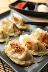 Delicious fried gyoza dumplings with sesame seeds served on table, closeup