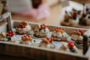 A beautifully arranged wooden tray filled with elegant layered cookies topped with fresh whipped...