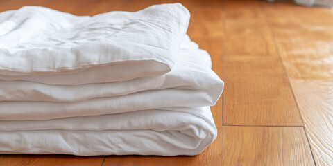 Stack of Folded White Cotton Sheets on Wood Floor