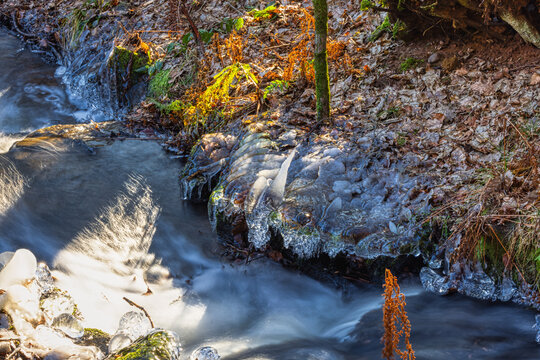 whitewater stream in winter, long exposure, water mist forms ice sculptures on the bank with phascinating light effects