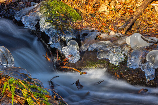 whitewater stream in winter, long exposure, water mist forms ice sculptures on the bank with phascinating light effects