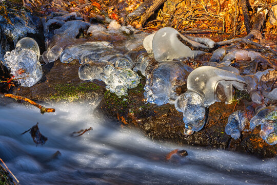 whitewater stream in winter, long exposure, water mist forms ice sculptures on the bank with phascinating light effects