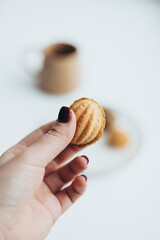A woman's hand holds a nut with condensed milk. Dessert for coffee.