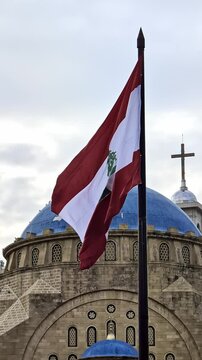 Beirut, Lebanon 01 26 2025: Al Amin mosque with blue domes and Christian church with a cross in downtown Beirut. Lebanese flag prominent. Diversity, religious coexistence, national identity. Vertical