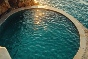 Sunlit circular pool overlooking ocean, cliffside setting.