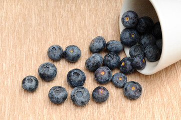 Fresh Blueberries Spilled from a White Ceramic Cup onto a Table