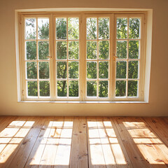 Fototapeta premium Sunlight streams through a multi-paned window, casting geometric shadows on a wooden floor in an otherwise empty room.