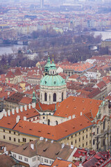 A panoramic view of a historic European city features a grand church with a green dome surrounded...