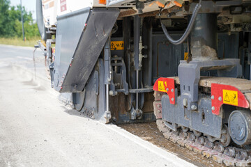 An asphalt milling machine operating on a highway construction site, close up.