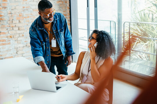 Colleagues engaged in a dynamic phone conversation at a bright modern office, sharing ideas for a successful project outcome