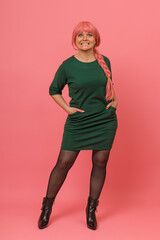 A woman in a green dress and wig grits her teeth as if she did something wrong while posing for the...