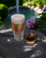 Cold milk coffee served on a wooden table with a view of the garden and fountain.