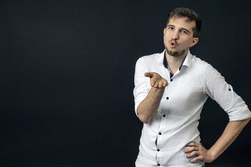a man in a white shirt sends an air kiss to the camera. empty space.