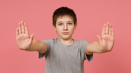 Teenager all T-shirts on a pink background stretched his palms forward
