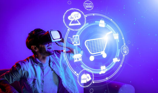 Happy man using VR headset and shopping online while sitting at sofa with shopping bags. Smart person looking at online market hologram and icon with neon background. Innovation technology. Deviation.