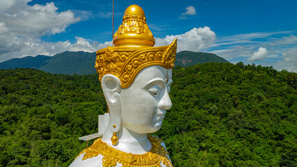 Close up the Tall Buddha Brahma Panyo statue standing tall in front of Doi Luang mountain, adorned...